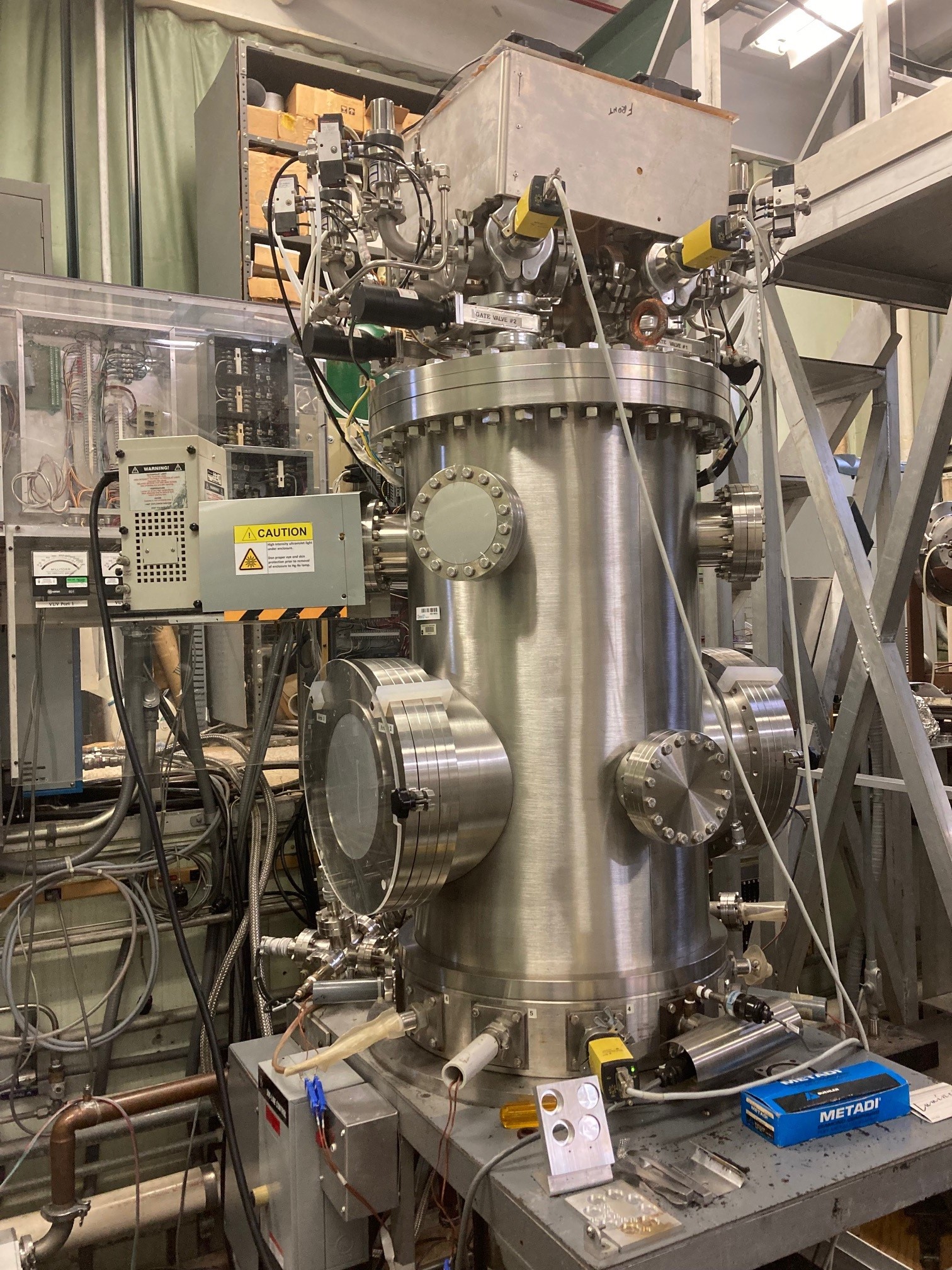 A cylindrical upright vacuum chamber has several ports and scientific instruments surrounding it.