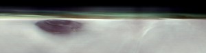 A black mountain peak shows through water ice clouds on Mars. Just above the clouds is the hazy green Martian atmosphere.