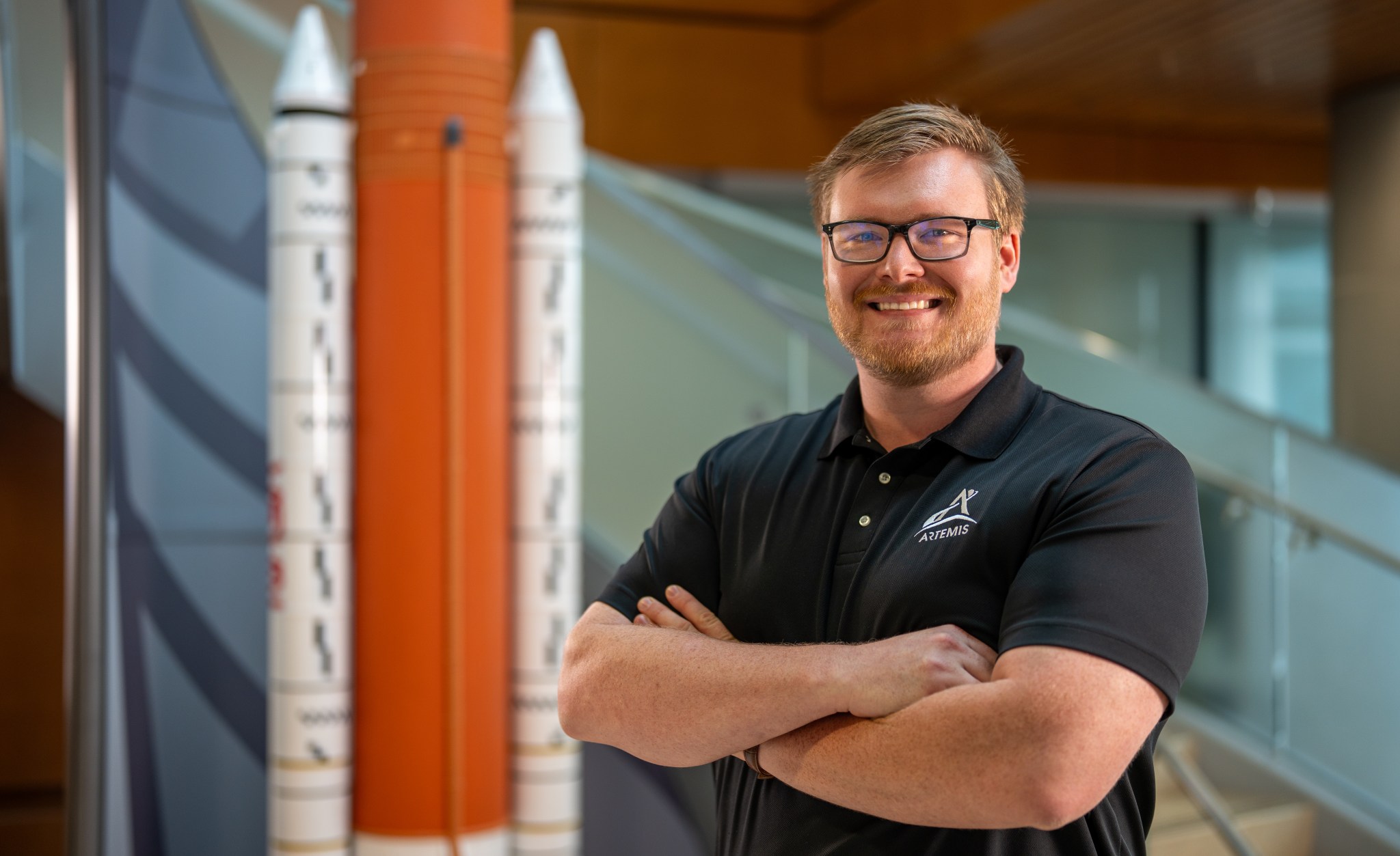 Patrick Junen stands beside a model of the Space Launch System.