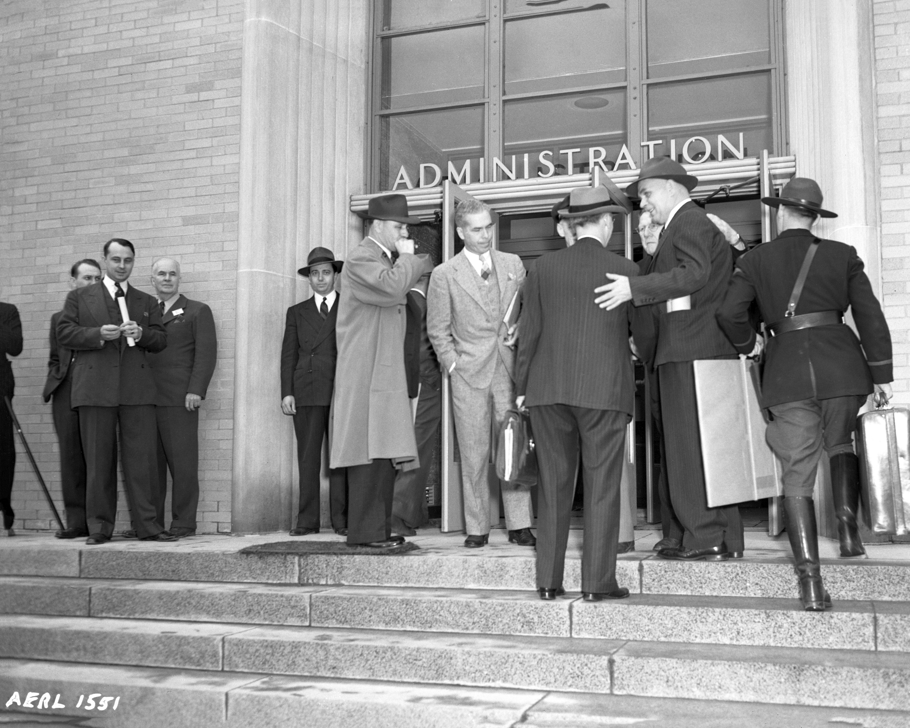 Group of men at front entrance to building.