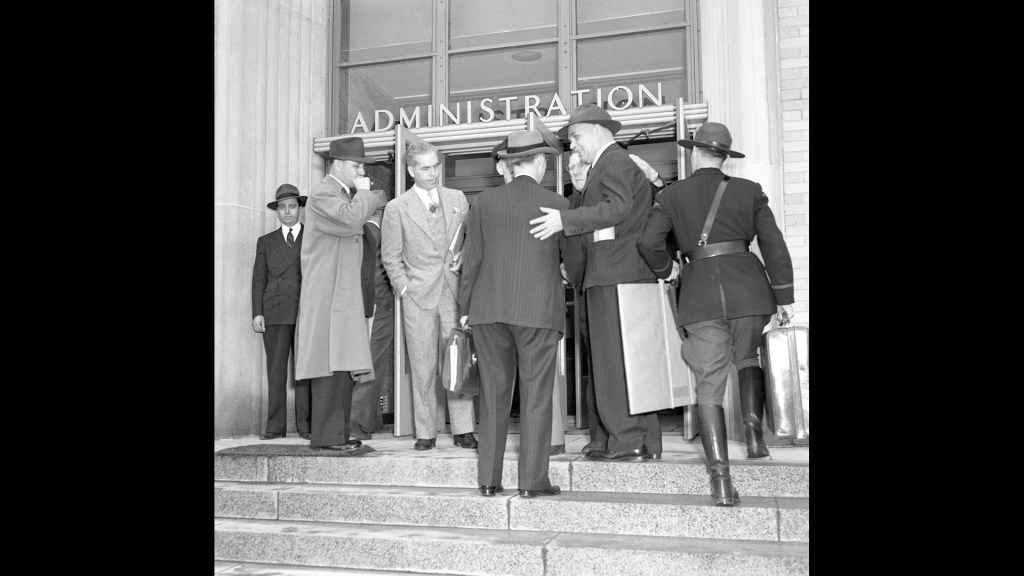 Group of men at front entrance to building.