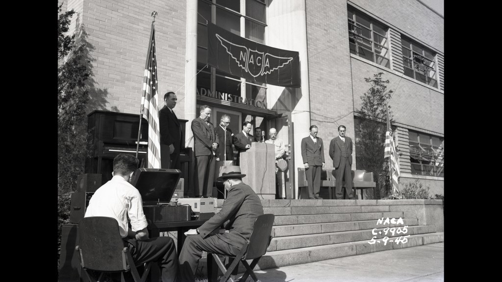 People outside building with heads bowed.