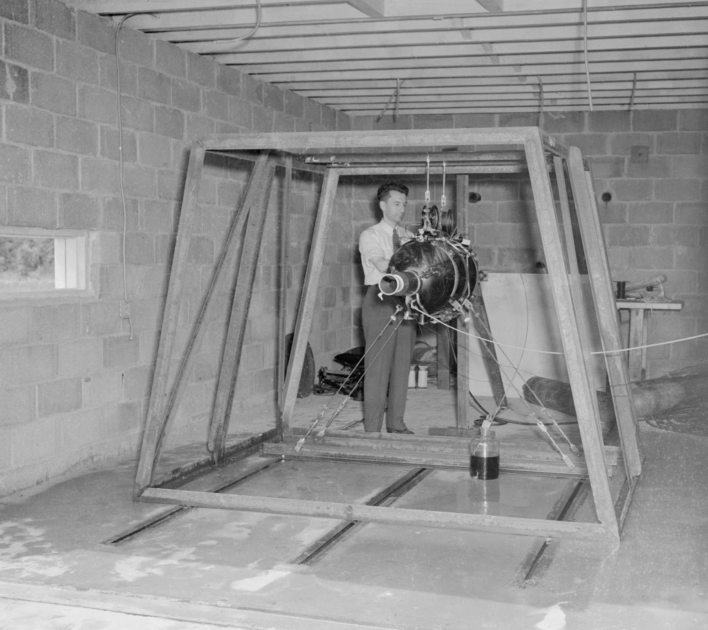 Man prepares rocket engine in test cell.