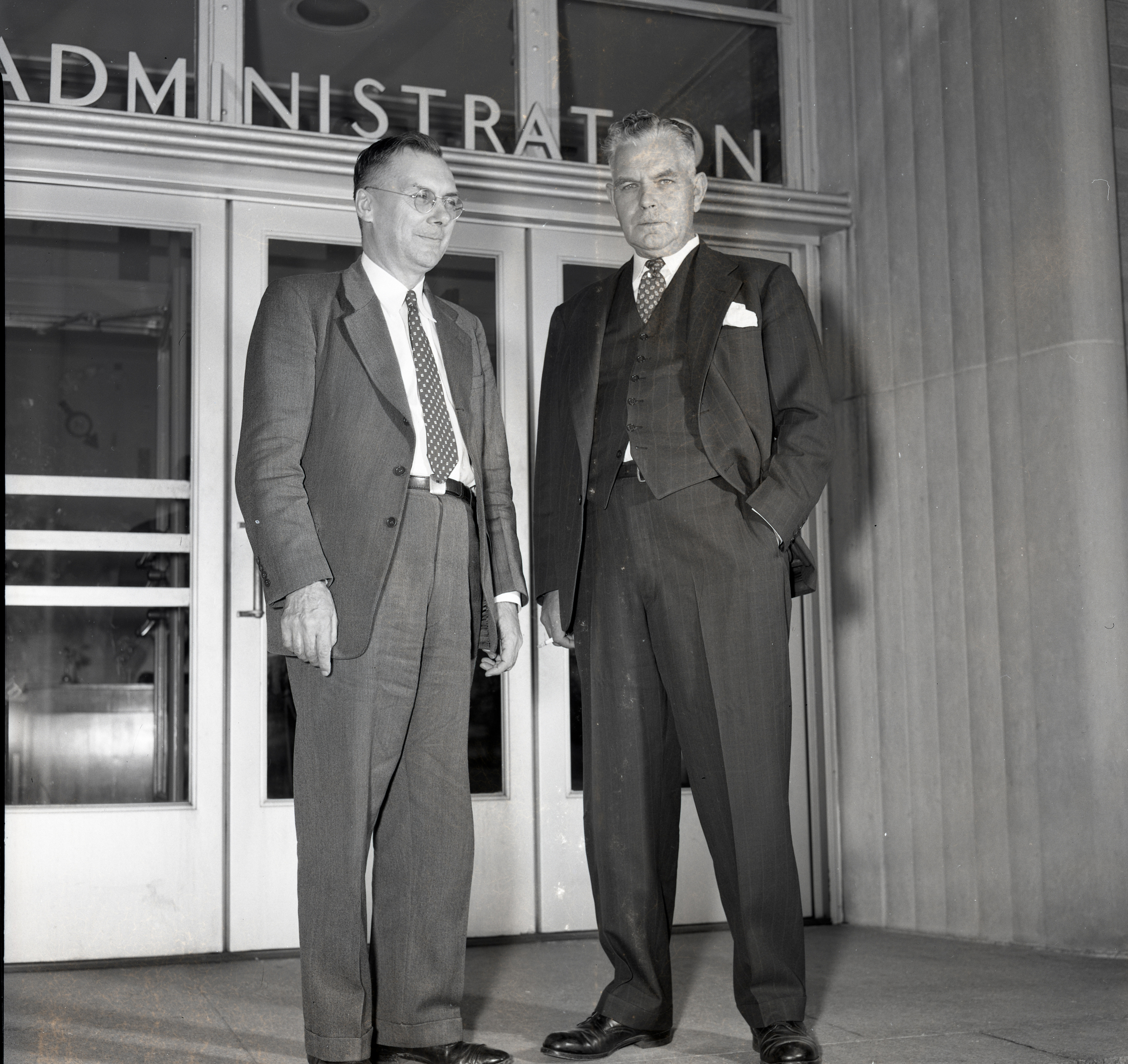 Two men standing outside building entrance.