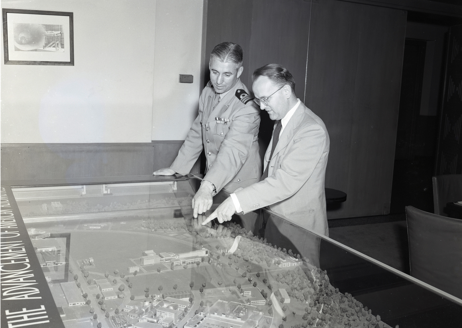 Two men looking down at campus model.