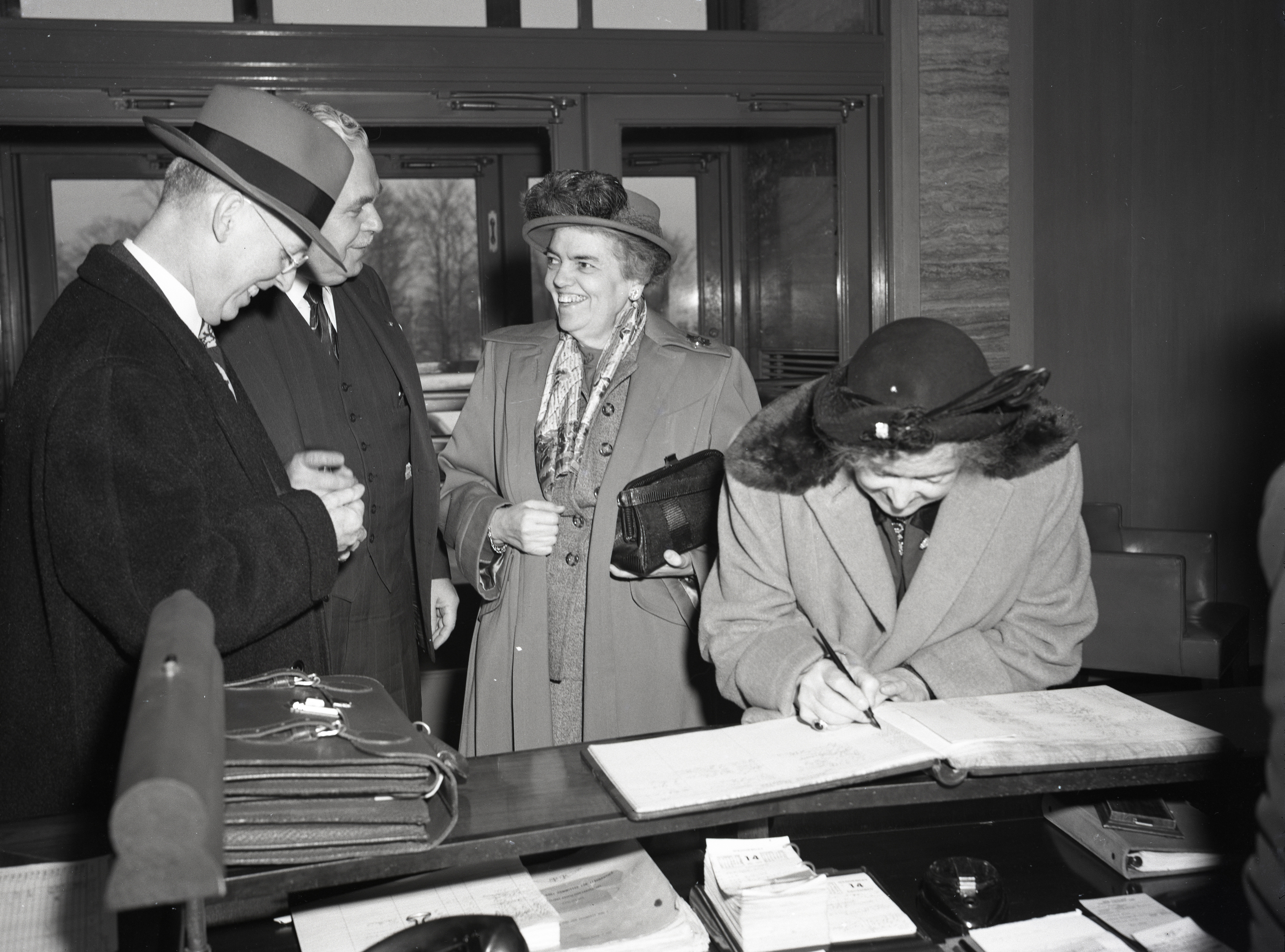 Women signing guestbook at lobby desk.