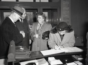 Women signing guestbook at lobby desk.