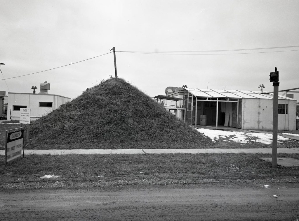 Mound next to small building.