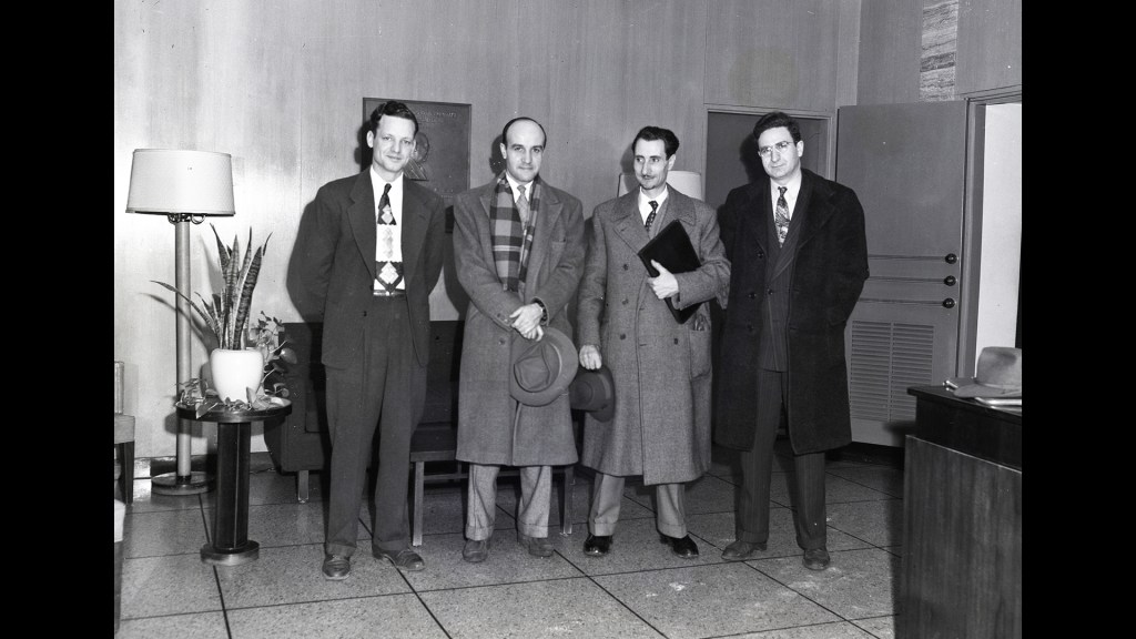 Four men standing in lobby.