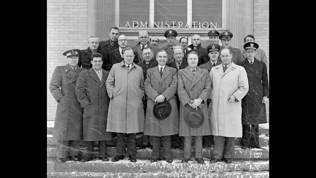 Group of men posing for photo on building steps.