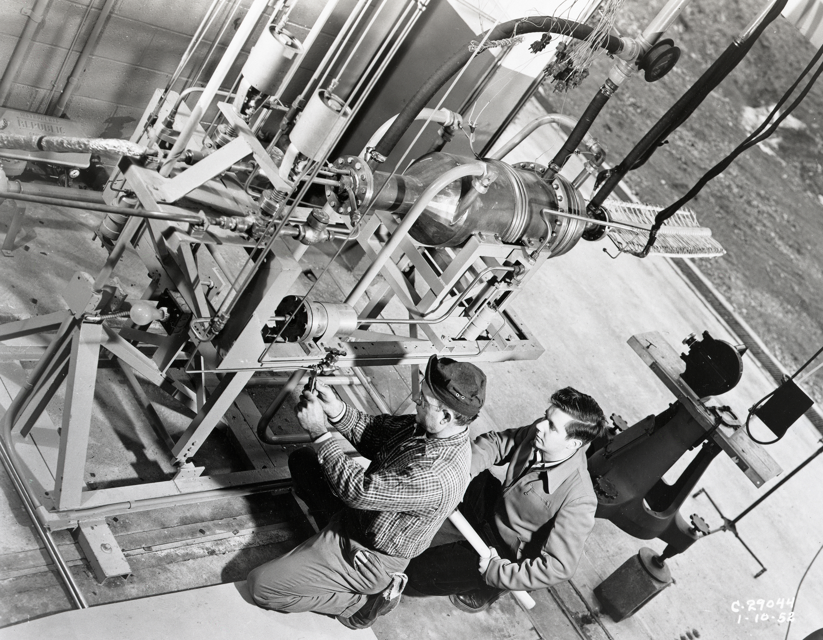 Two technicians working on a small rocket engine.