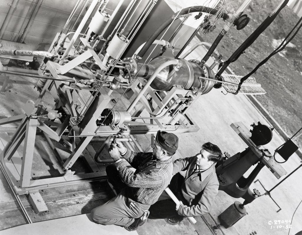 Two technicians working on a small rocket engine.