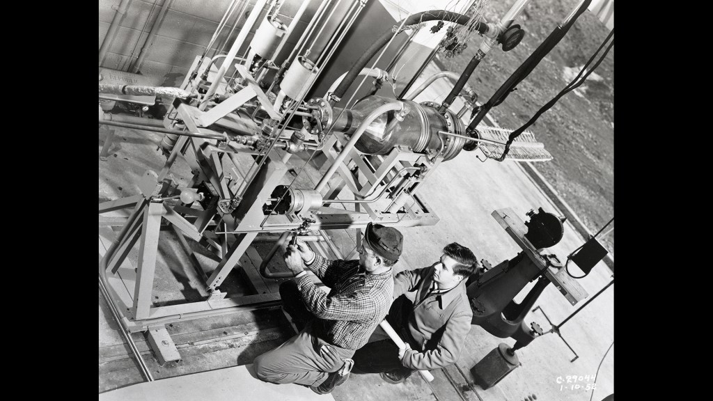 Two technicians working on a small rocket engine.