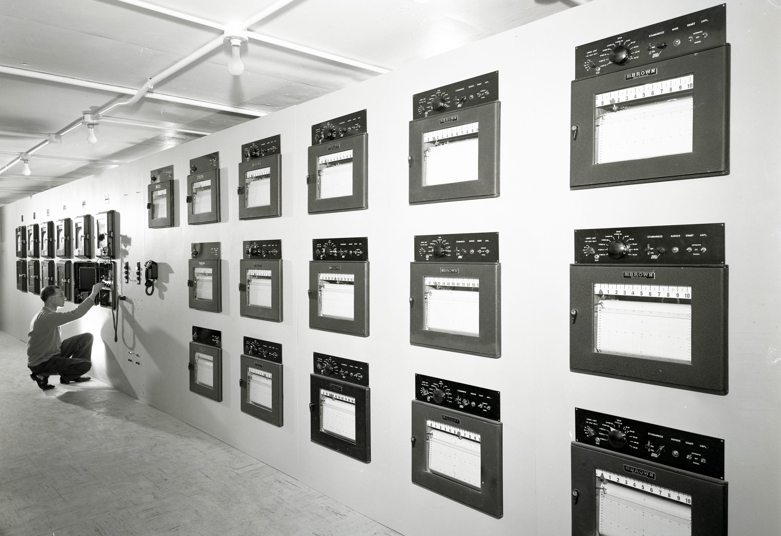 Man looking at data recorders on wall.