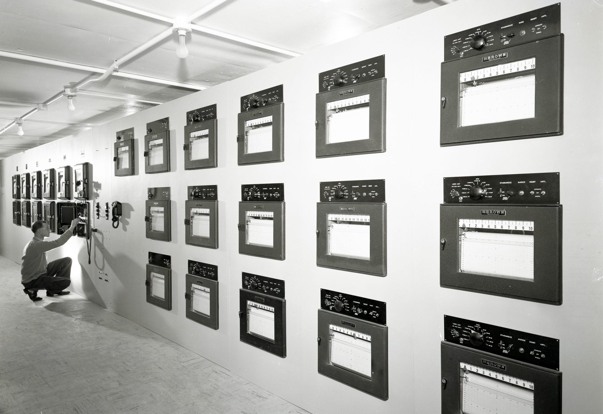 Man looking at data recorders on wall.