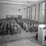 Man speaking to auditorium from podium.