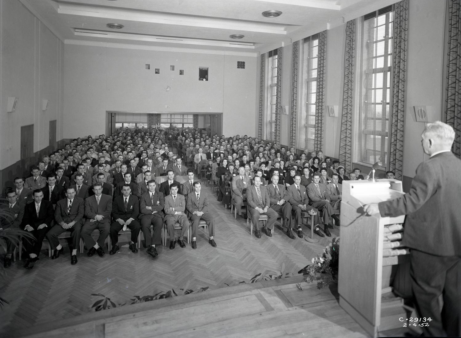 Man speaking to auditorium from podium.
