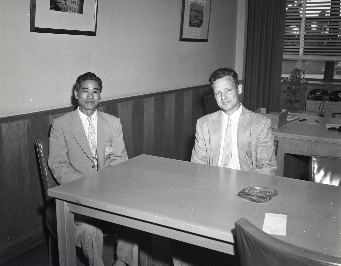 Two men sitting at table in office.