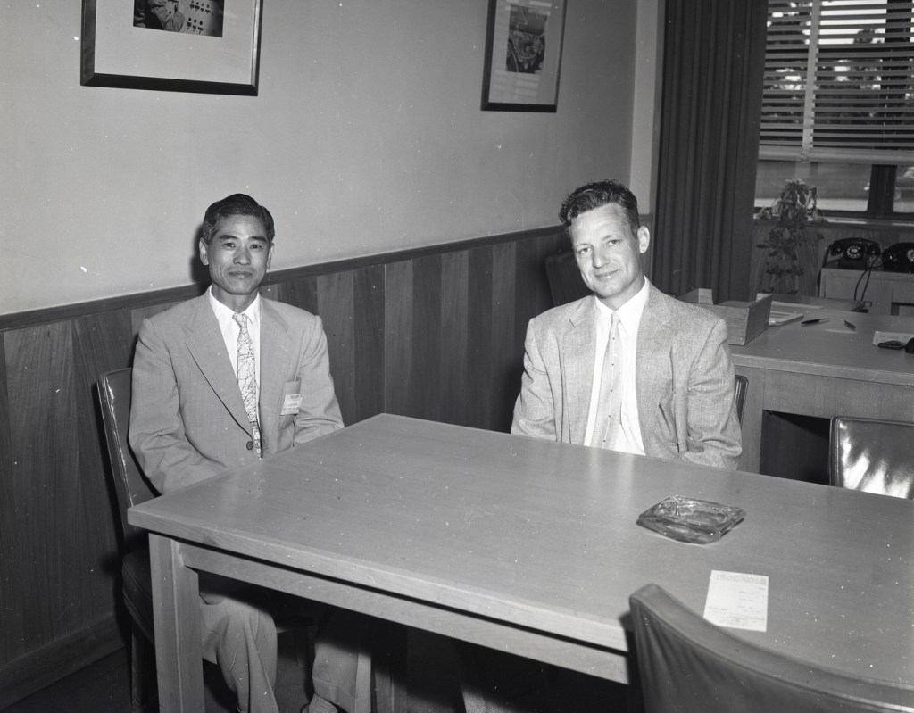 Two men sitting at table in office.