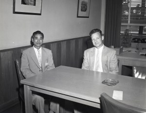 Two men sitting at table in office.