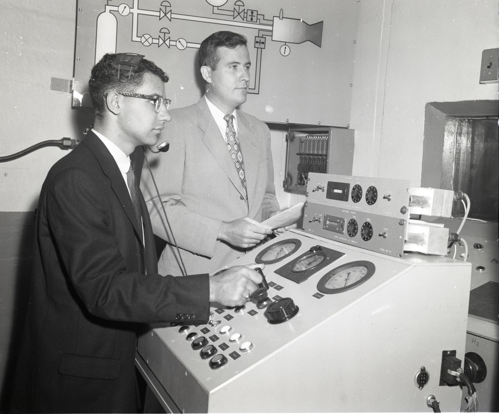 Two men at control panel.