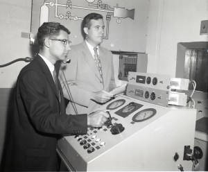 Two men at control panel.