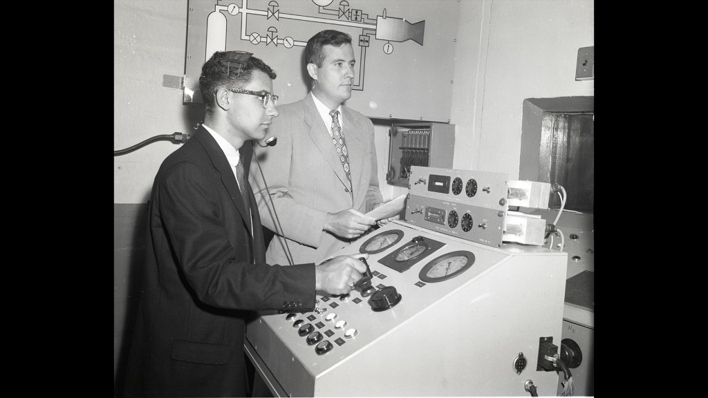 Two men at control panel.