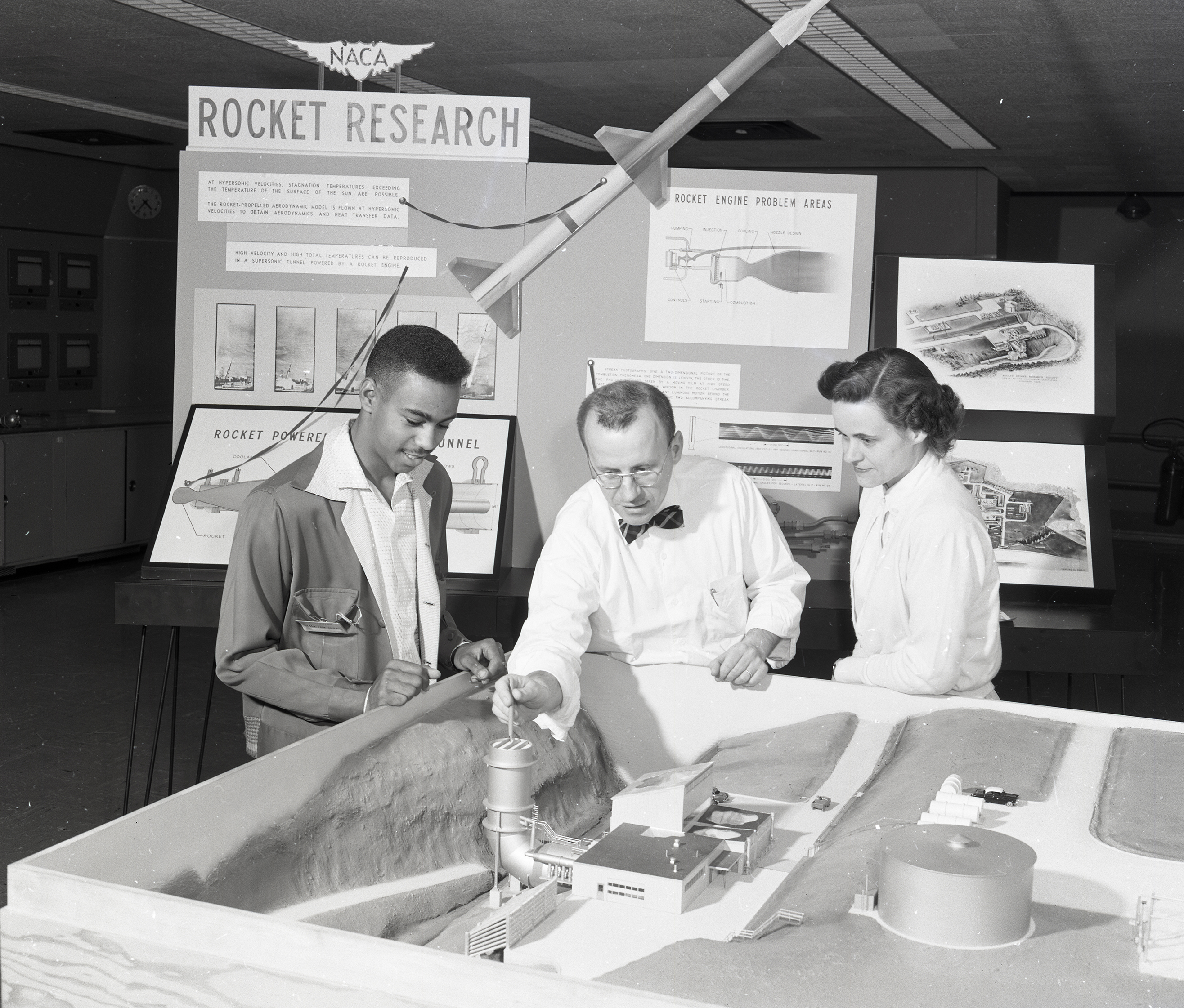 Three people examining model of the RETF.