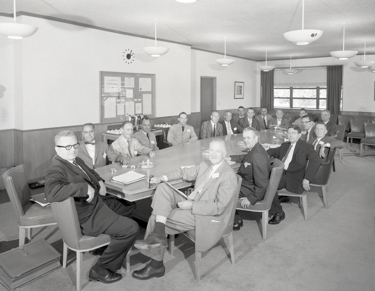 Group of men seated at conference table.