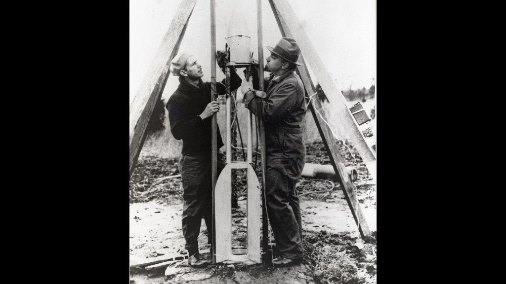 Two men adjust a rocket