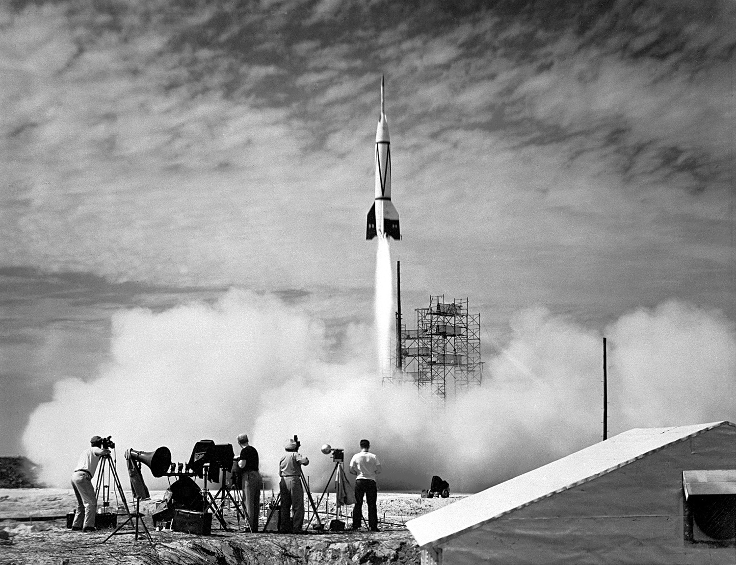 Rocket launch with camera men in the foreground.