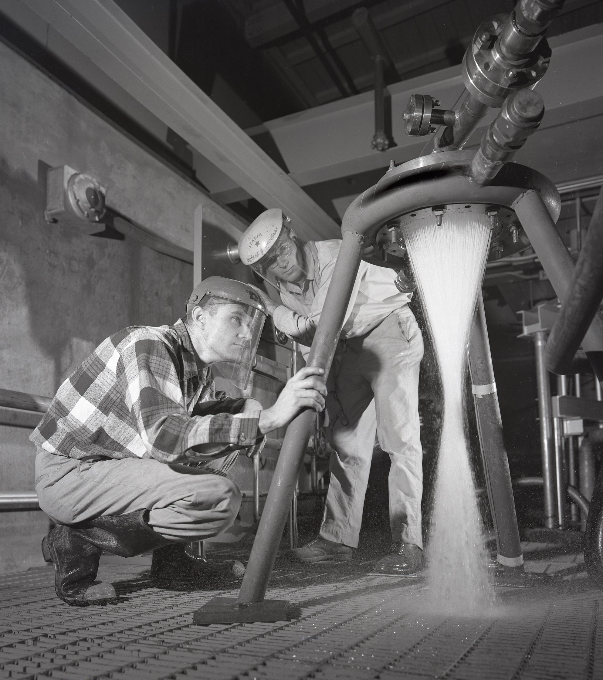 Two technicans watching water flow through injector.