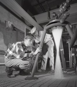 Two technicans watching water flow through injector.