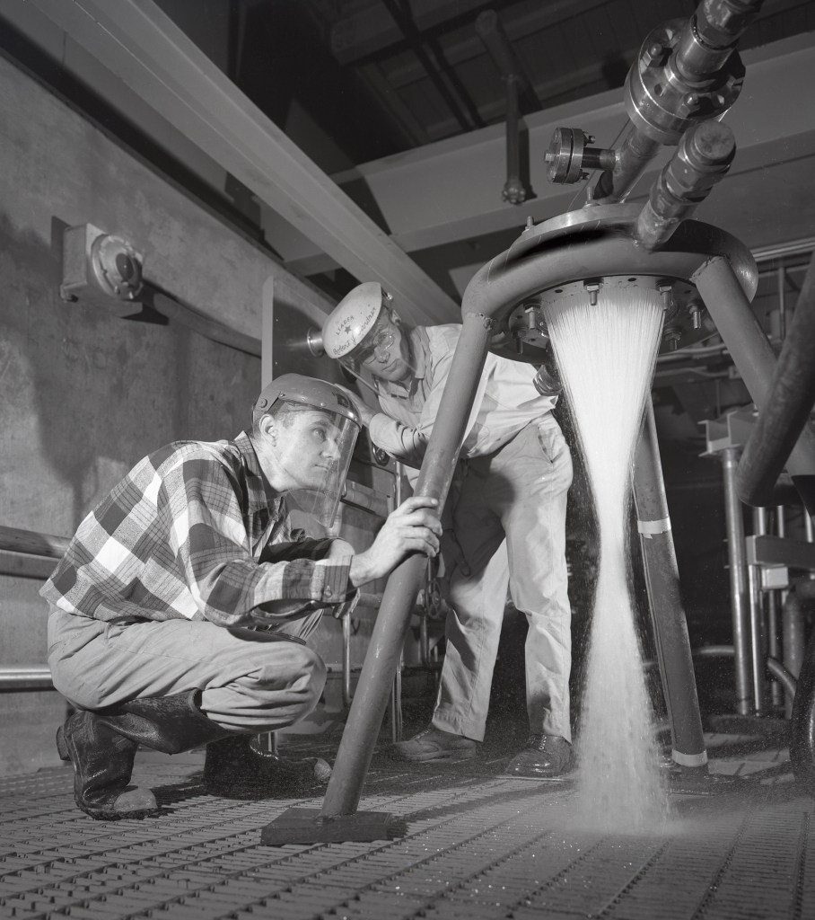 Two technicans watching water flow through injector.