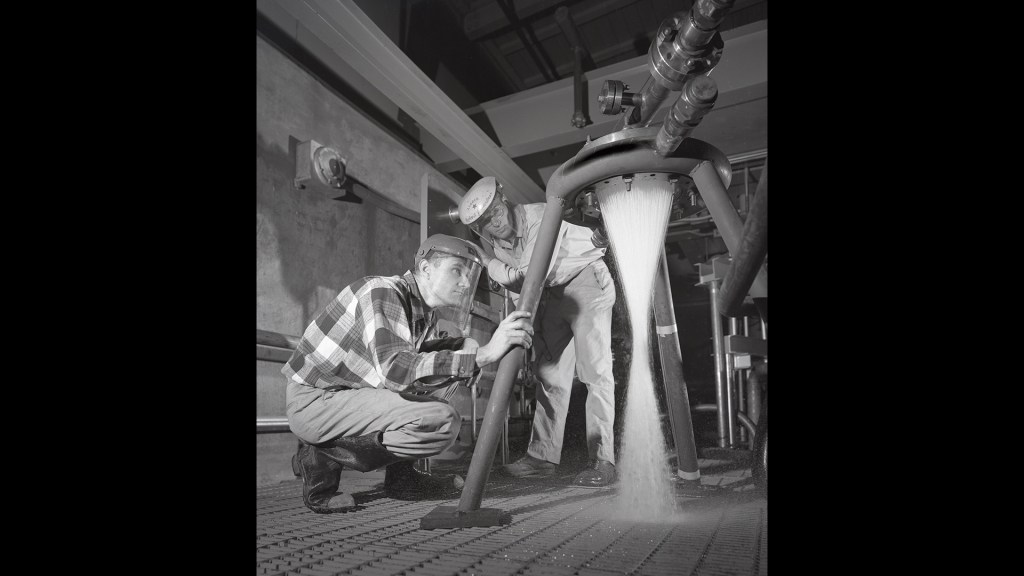 Two technicans watching water flow through injector.