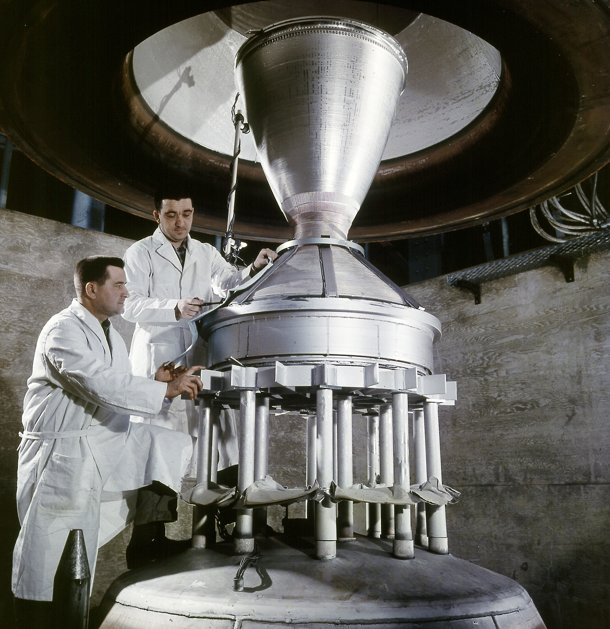 Two men looking at rocket nozzle.