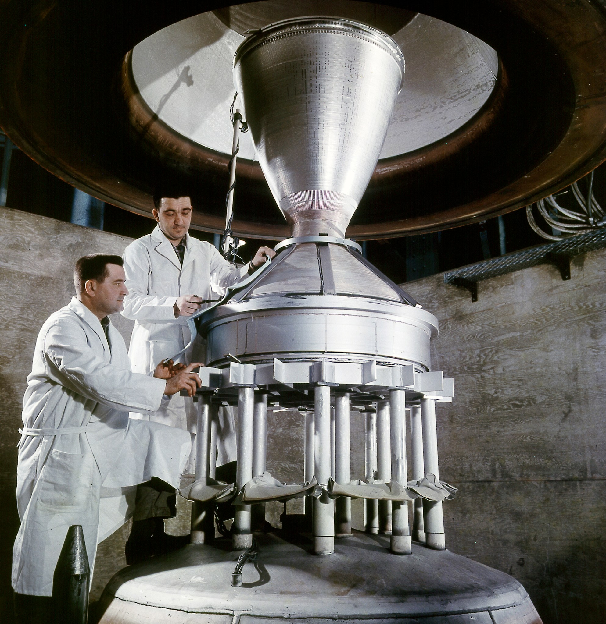 Two men looking at rocket nozzle.