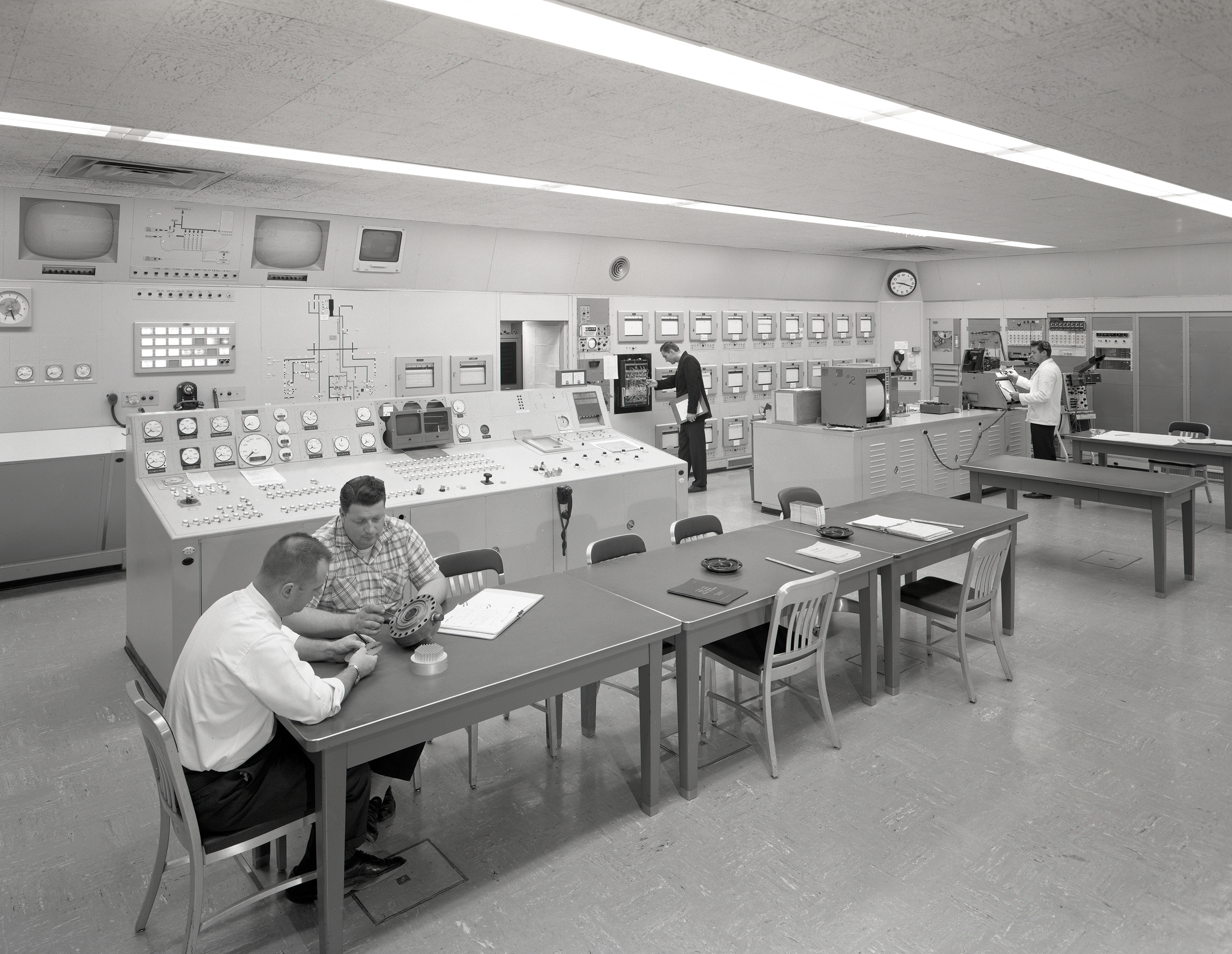 Men at various stations in control room