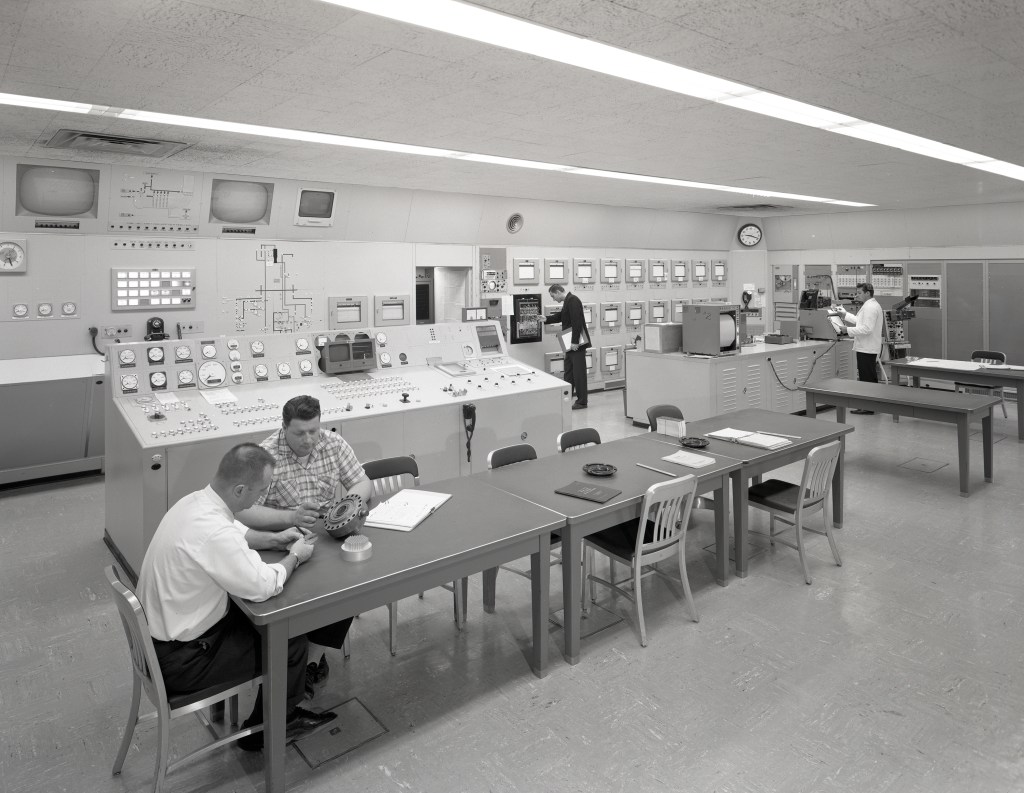 Men at various stations in control room