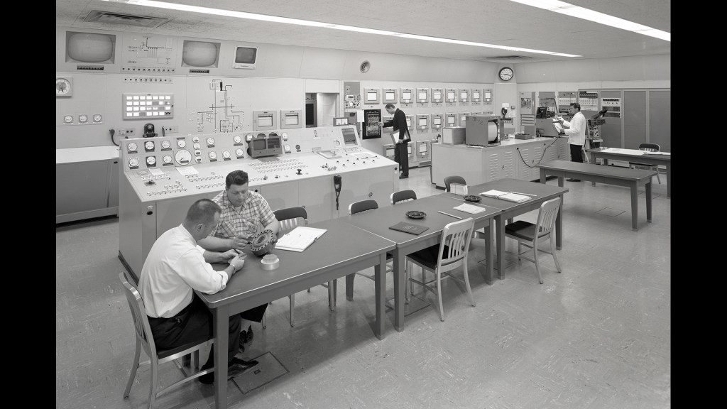 Men at various stations in control room