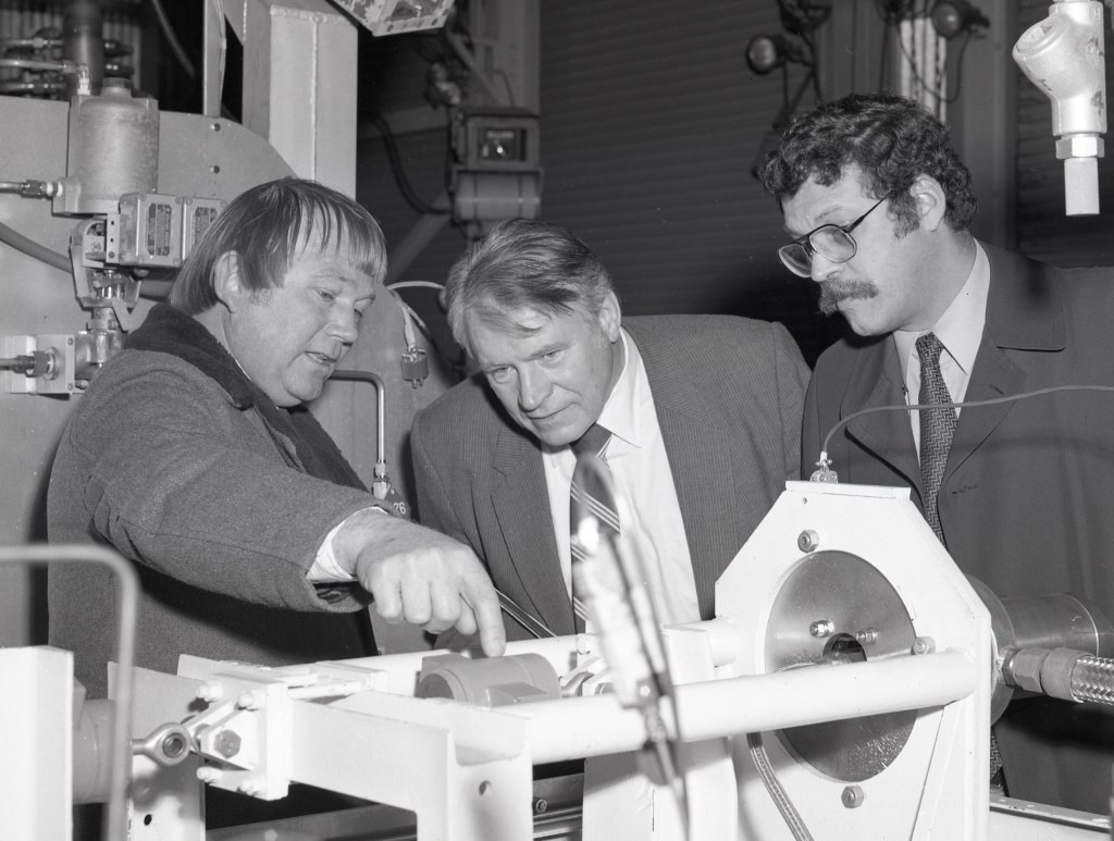 Three men examining hardward.