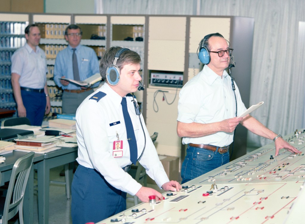 Four men in control room.