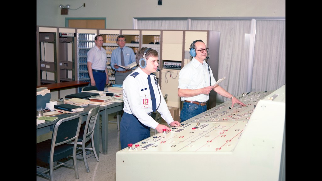Four men in control room conducting test