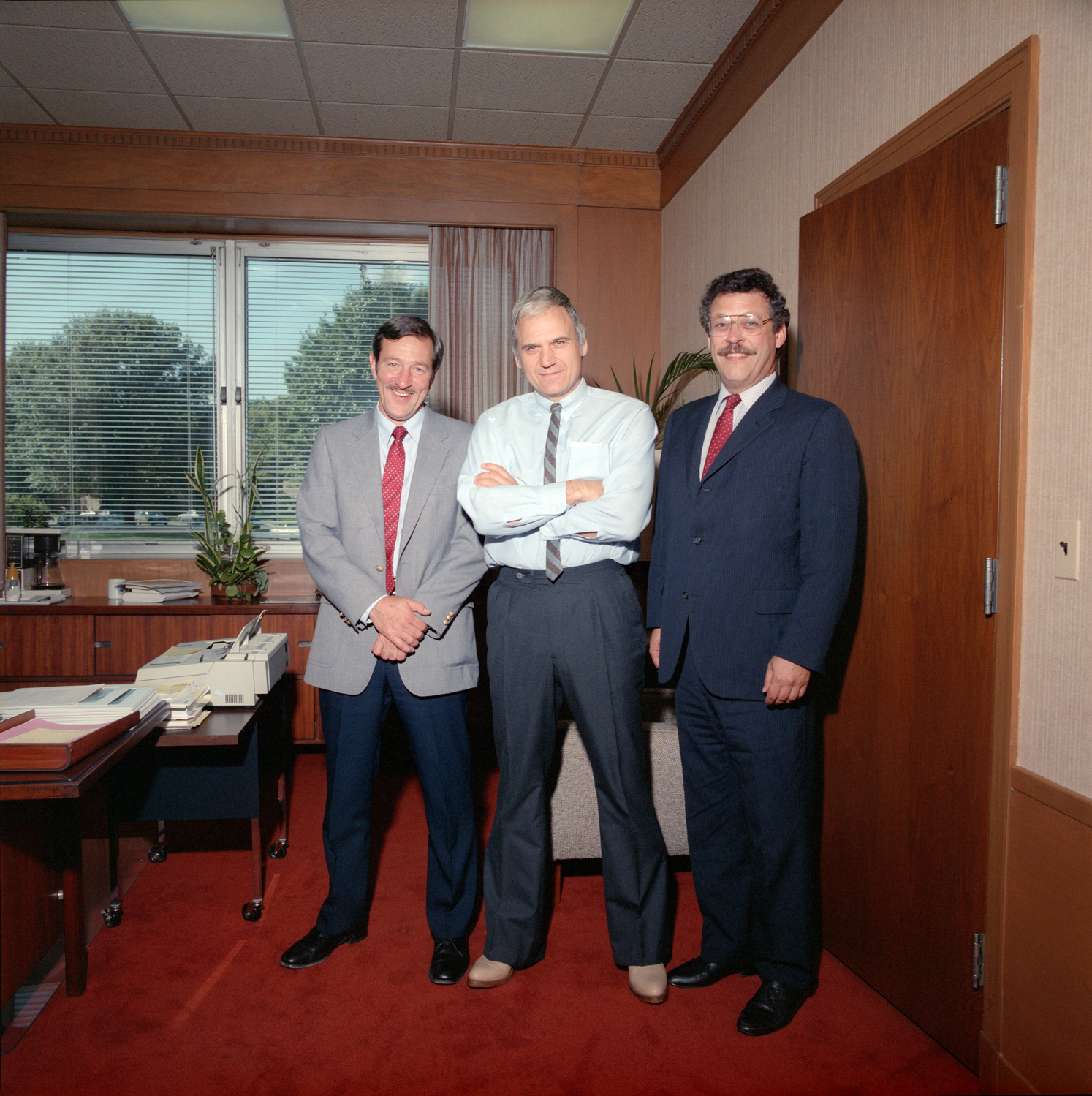 Three men standing in office.