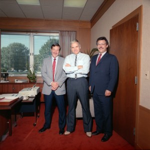 Three men standing in office.