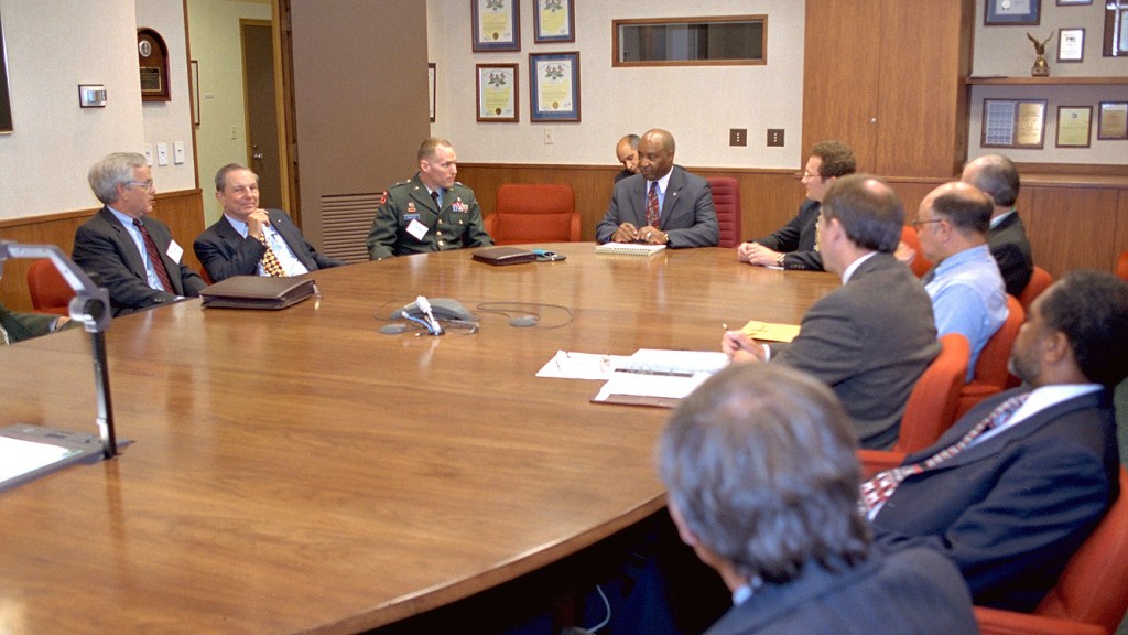 Group of men seated at conference table.