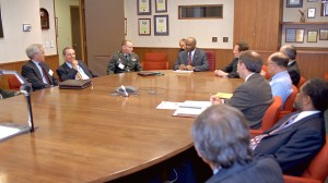 Group of men seated at conference table.