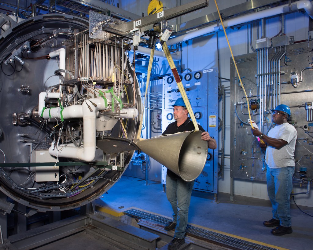 Technicians install engine on test stand.