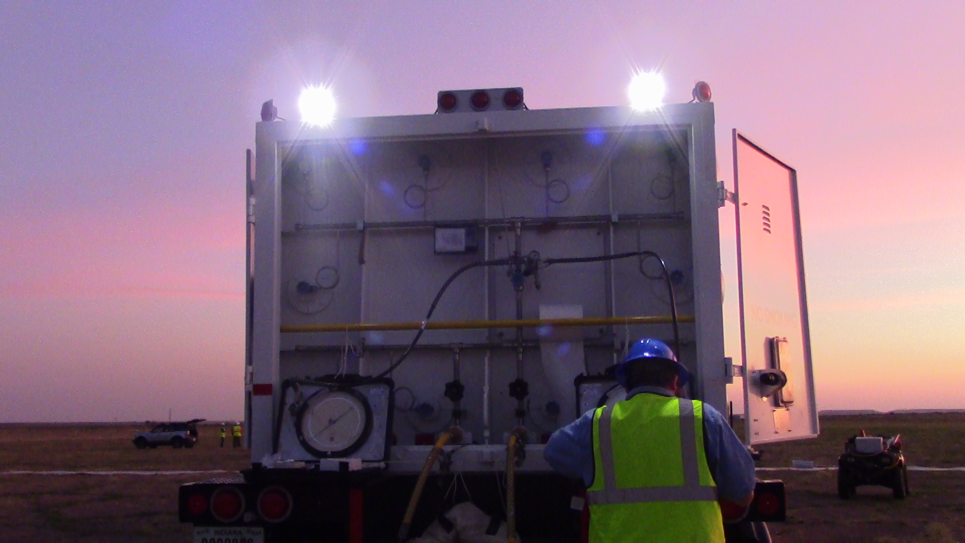 Person looking at a balloon payload at sunrise.
