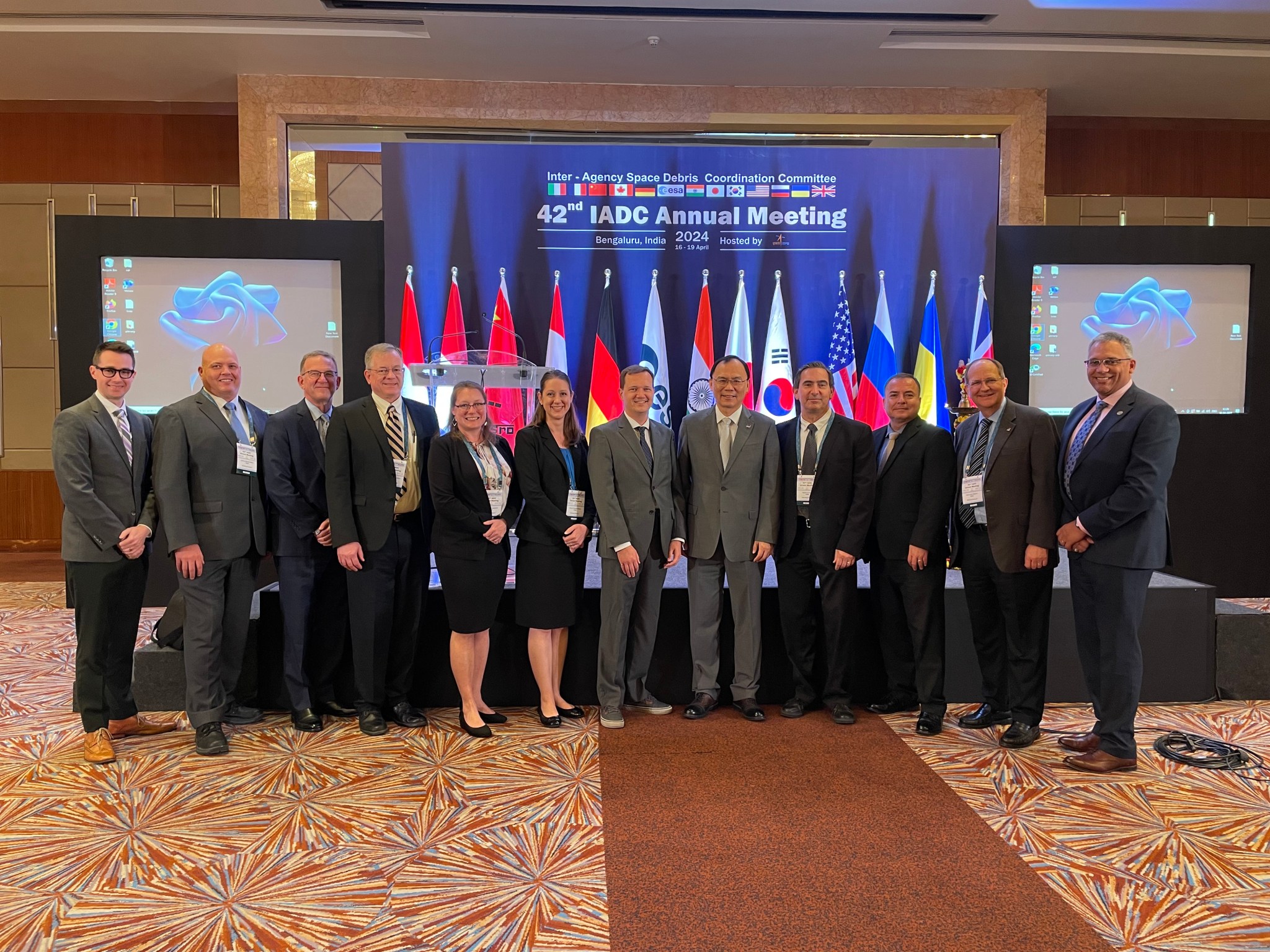 Twelve people pose in business suits at a conference center.